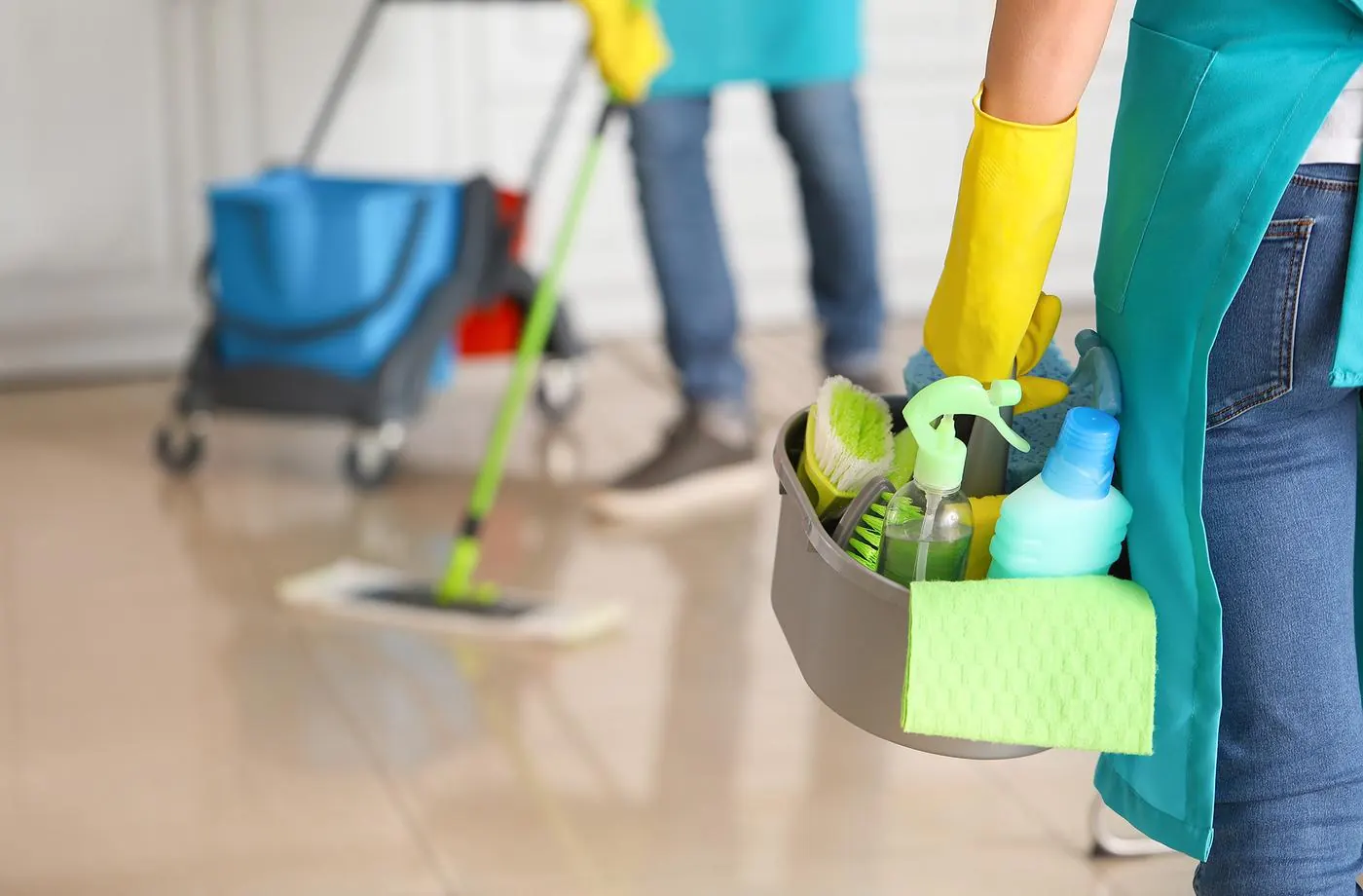 Cleaner holding a caddy of cleaning supplies